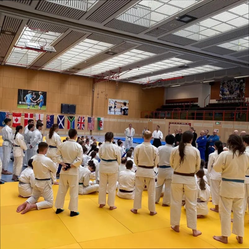 Summer Training - Jitsuka looking at instructors teaching on a yellow mat, illuminated by the summer sun